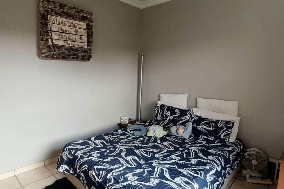 A bedroom featuring neutral wall tones, tiled flooring, and a ceiling fan, providing a functional space ready for personalization.