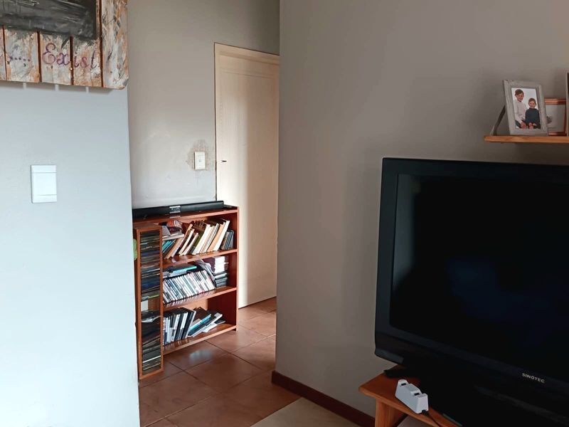 A view of a living area featuring tiled flooring and a doorway leading to an adjacent room, with visible wall surface wear.