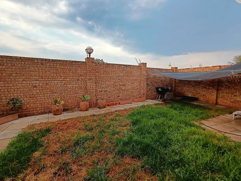 Private rear garden featuring a brick boundary wall with electric fencing and a paved patio area, offering potential for landscaping and outdoor living.