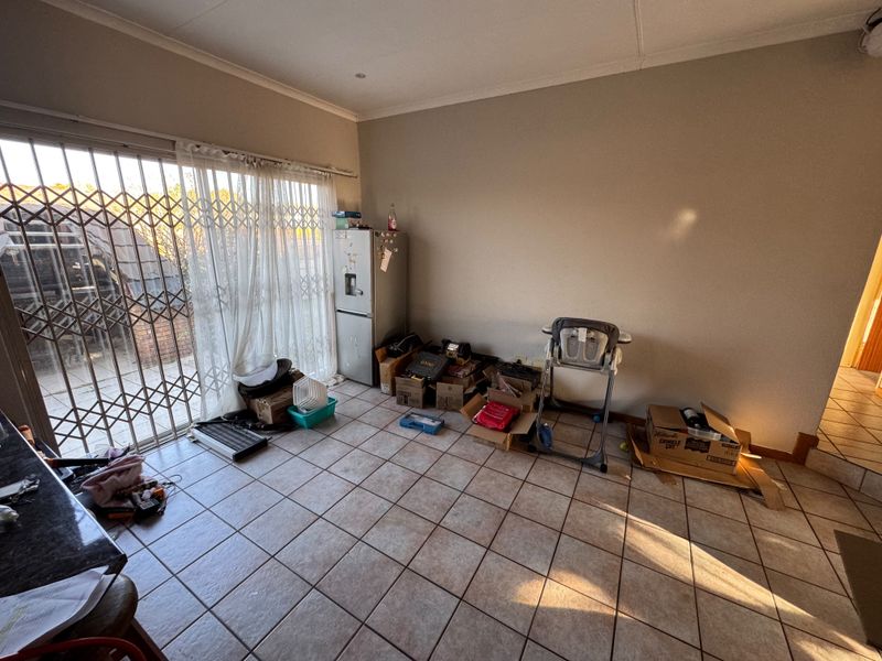 A living area featuring ceramic floor tiles and a sliding glass door with a security gate, providing access to the exterior.