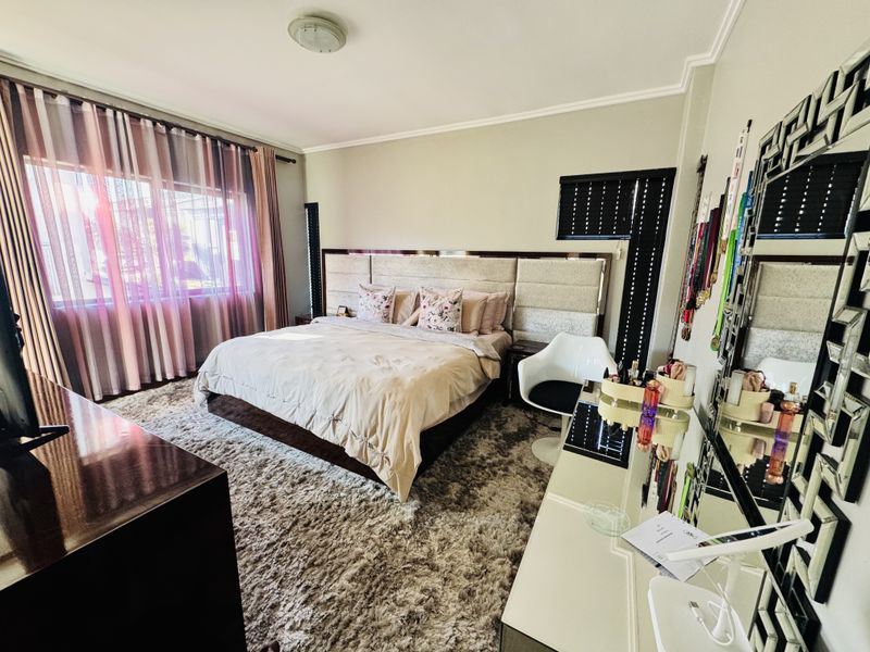A well-maintained bedroom featuring a large built-in headboard and neutral wall finishes, providing a comfortable and functional sleeping space.