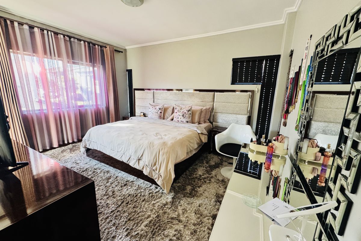 A well-maintained bedroom featuring a large built-in headboard and neutral wall finishes, providing a comfortable and functional sleeping space.