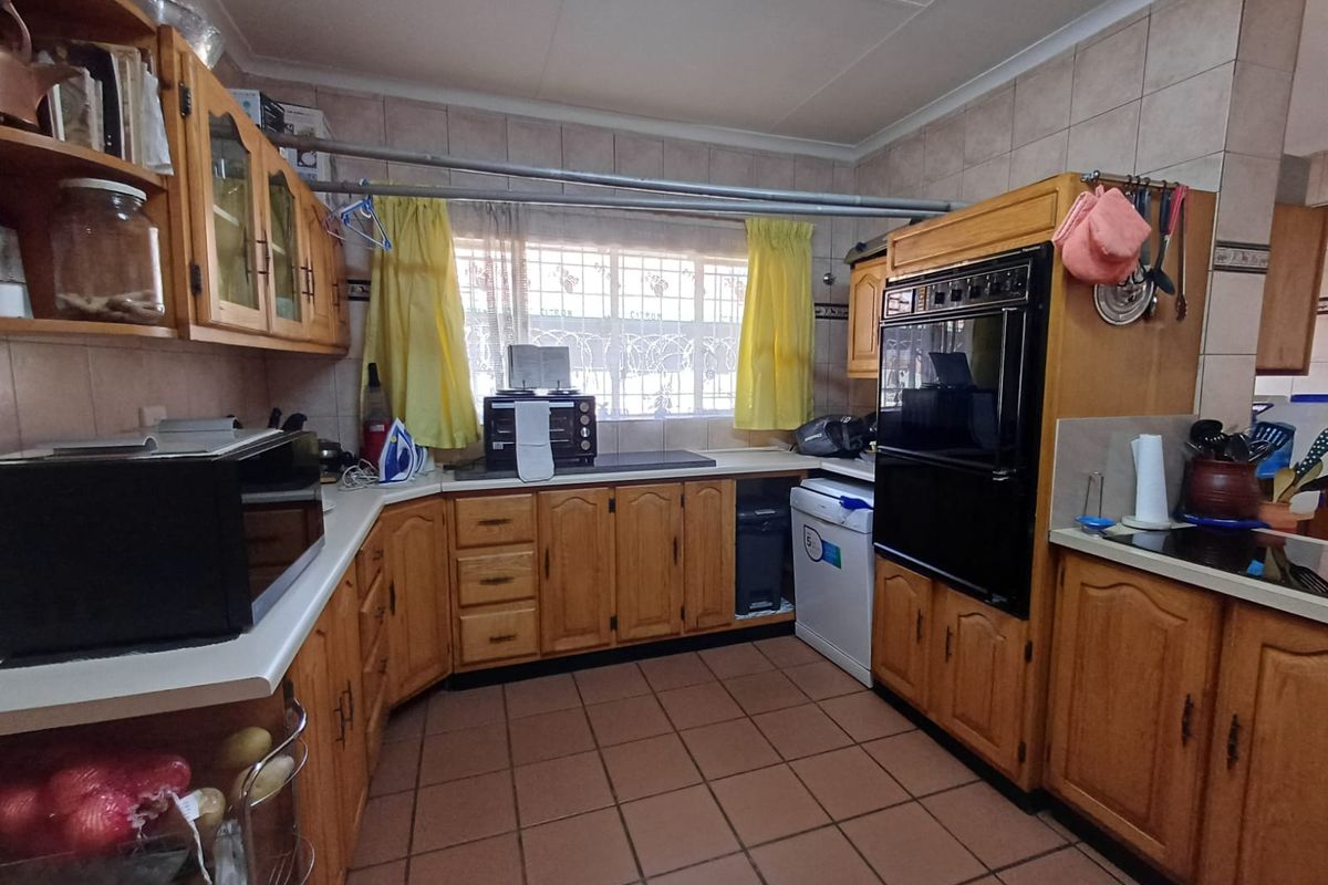 A functional kitchen featuring traditional wooden cabinetry, tiled flooring, and a built-in double oven, offering a classic layout with potential for modern updates.