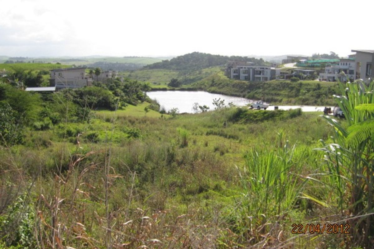 A scenic view of the surrounding landscape featuring natural vegetation and a nearby water body within a residential estate setting.