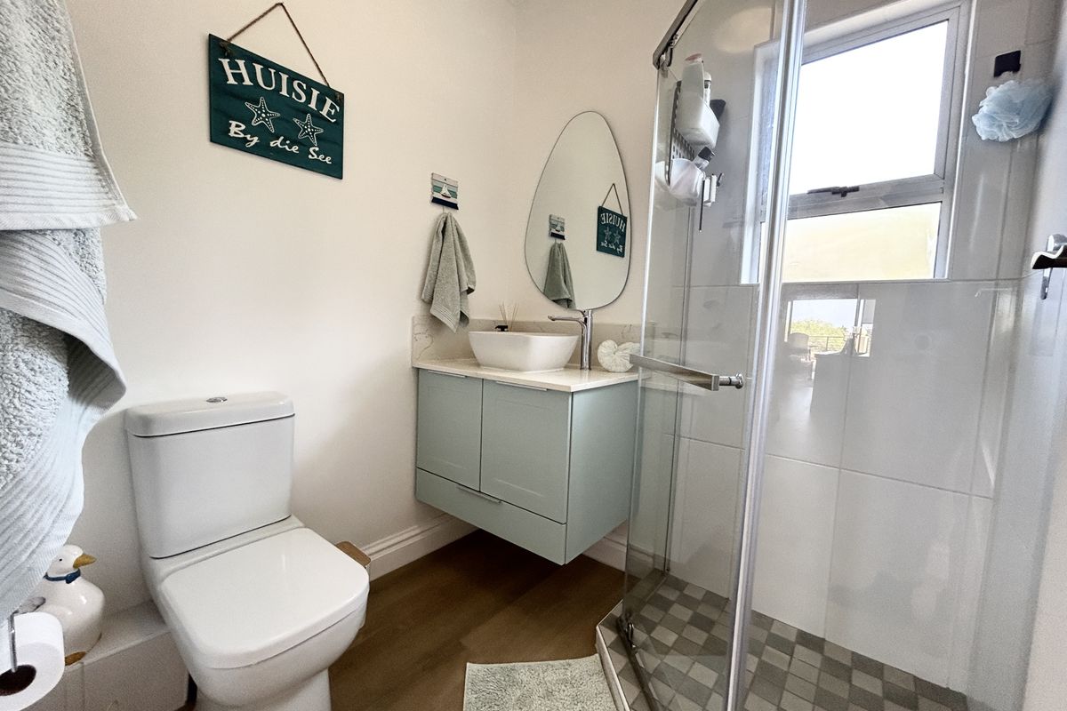 A modern bathroom featuring a floating vanity with a vessel sink, a glass-enclosed shower, and neutral finishes.