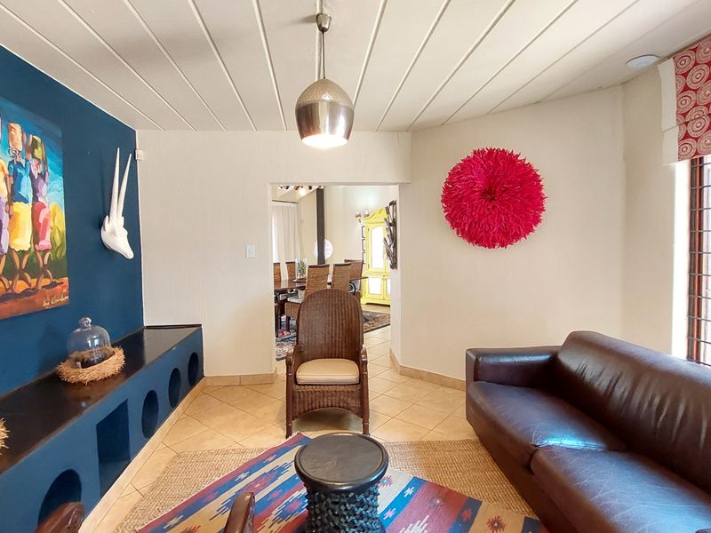 A living room featuring tiled flooring, built-in shelving, and a pendant light, with an open transition to the adjacent dining area.