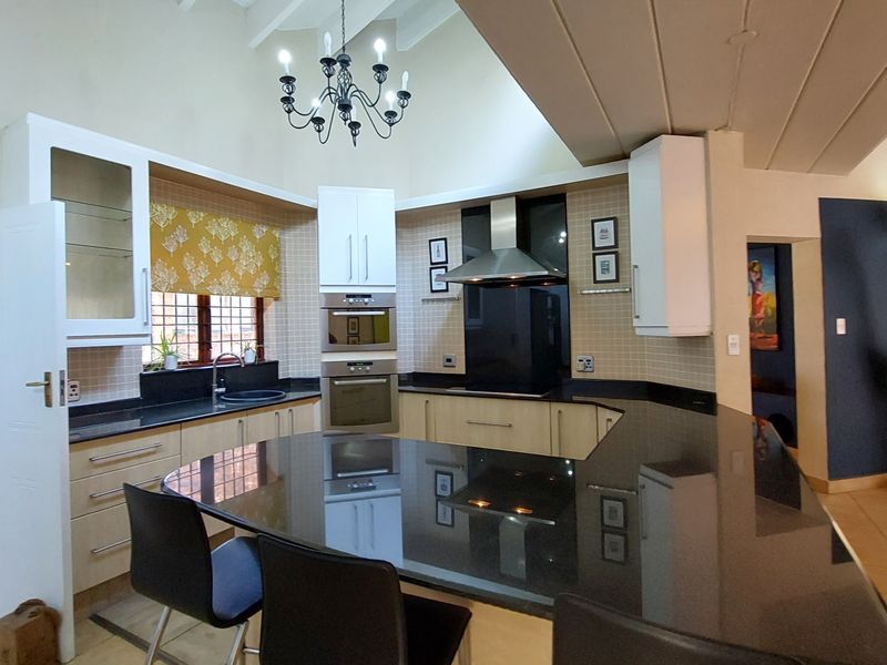 Spacious kitchen featuring granite countertops, a breakfast bar, built-in oven and microwave, and a vaulted ceiling with a feature chandelier.
