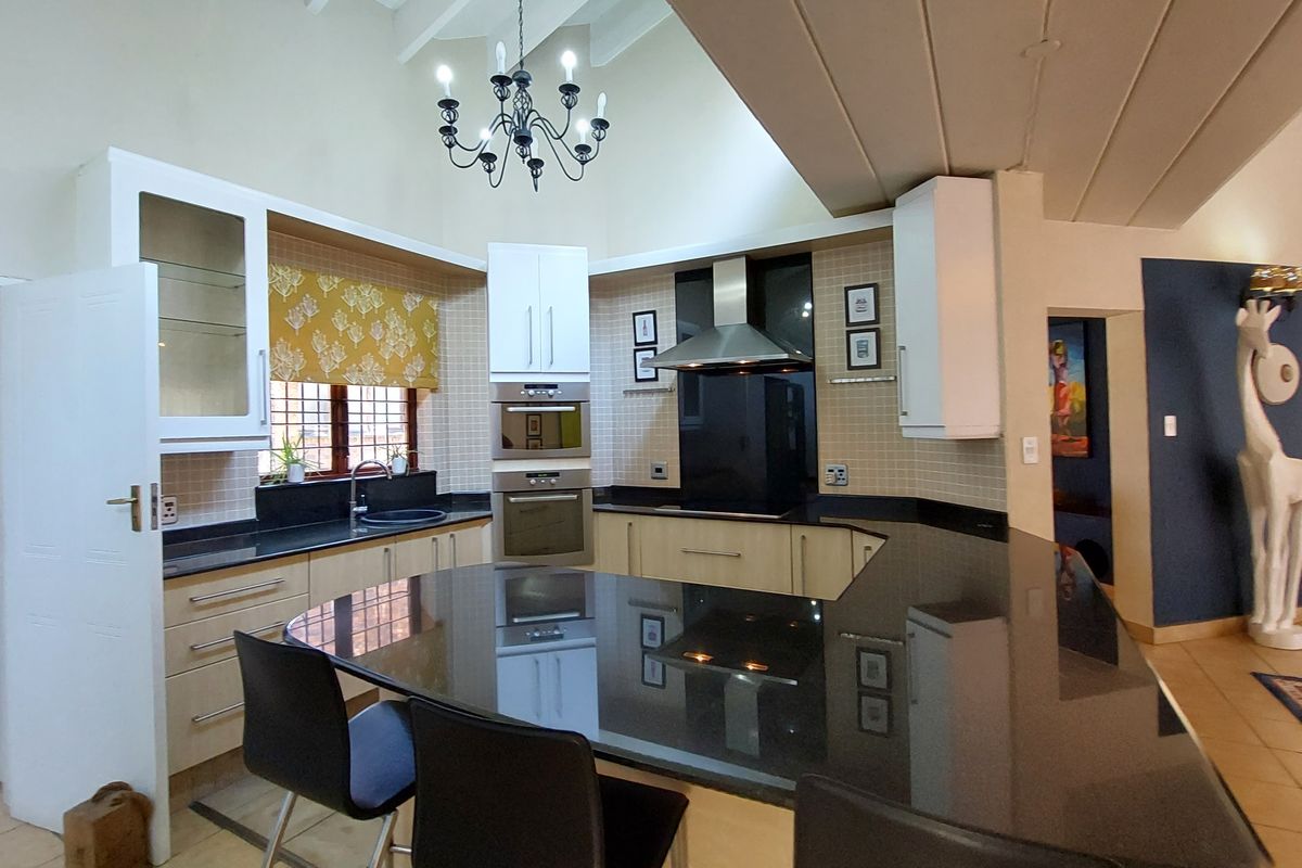 Spacious kitchen featuring granite countertops, a breakfast bar, built-in oven and microwave, and a vaulted ceiling with a feature chandelier.