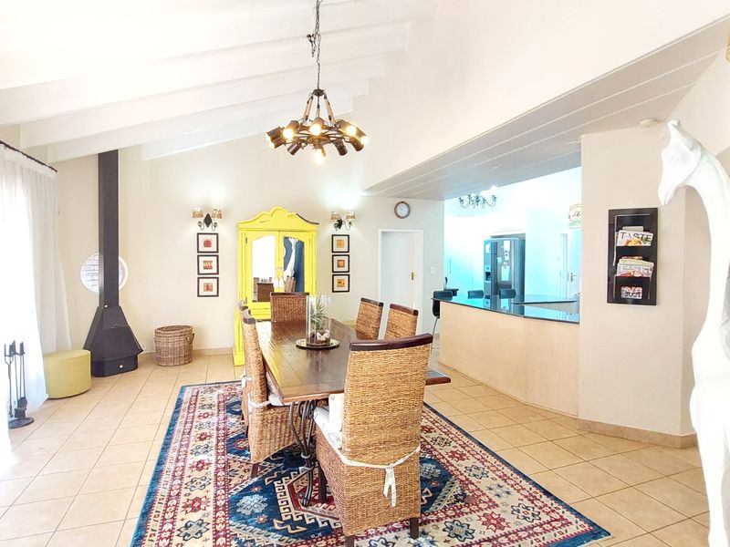Spacious open-plan dining and kitchen area featuring vaulted ceilings, tiled flooring, and a modern freestanding fireplace.
