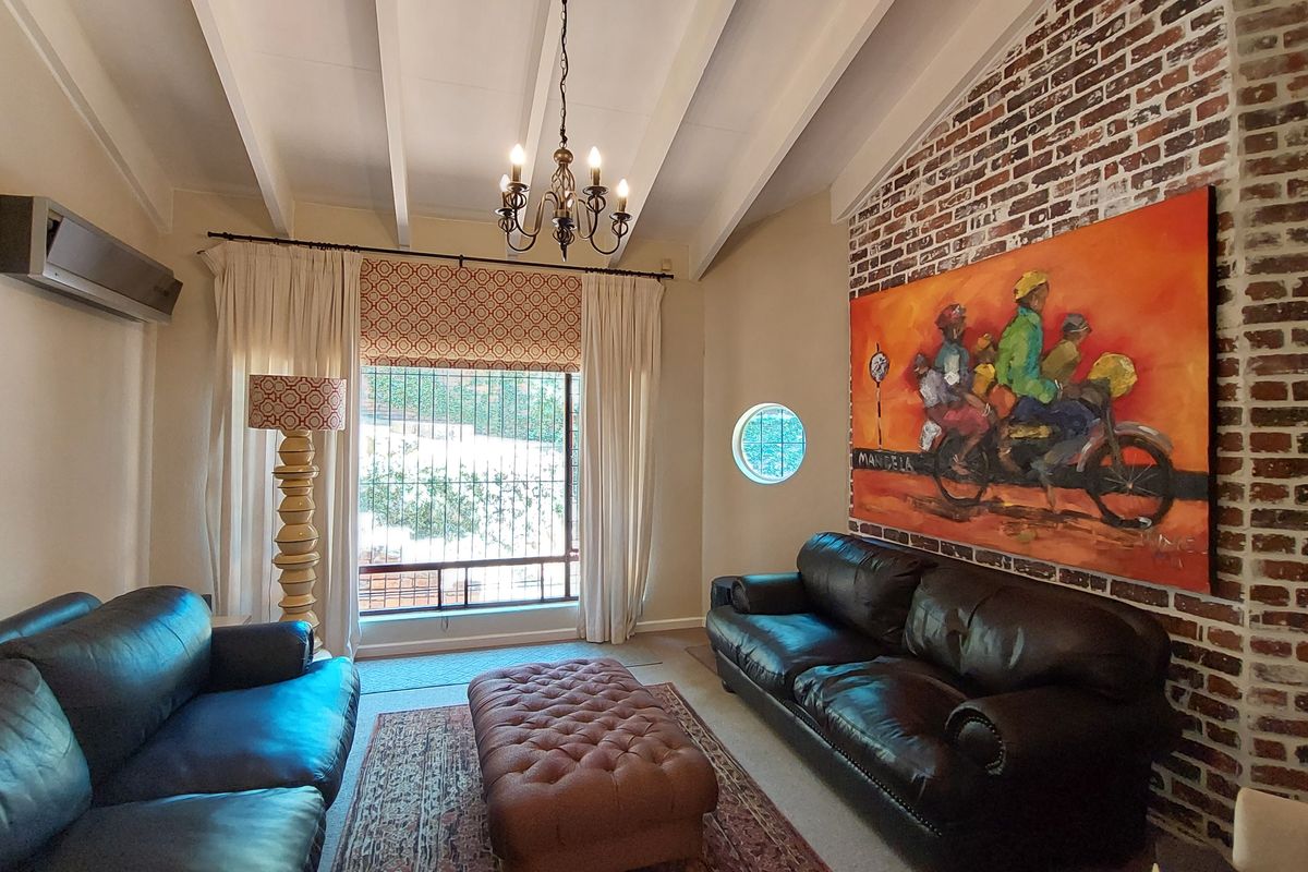 A cozy living room featuring a striking exposed brick feature wall, vaulted ceilings with exposed beams, and a unique circular window.
