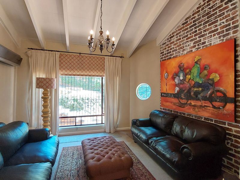 A cozy living room featuring a striking exposed brick feature wall, vaulted ceilings with exposed beams, and a unique circular window.