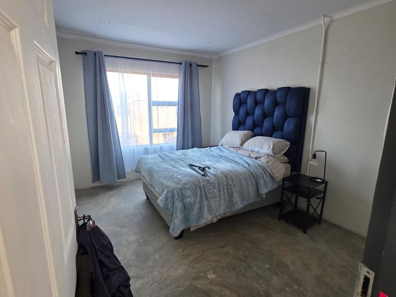 A bedroom featuring exposed concrete flooring and surface-mounted electrical conduit, offering a blank canvas for potential interior design updates.