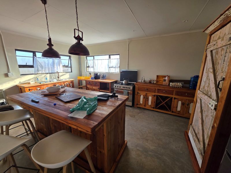 Rustic kitchen featuring a large wooden island, freestanding stove, double sink, and concrete flooring with ample natural light from multiple windows.