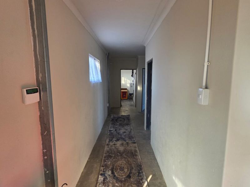 A narrow hallway featuring exposed electrical conduit and an unfinished structural column, requiring cosmetic updates to improve the overall aesthetic.