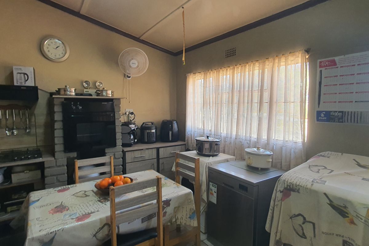 A functional kitchen featuring brick-built cabinetry, a built-in oven, gas hob, and extractor fan, with ample natural light from large windows.