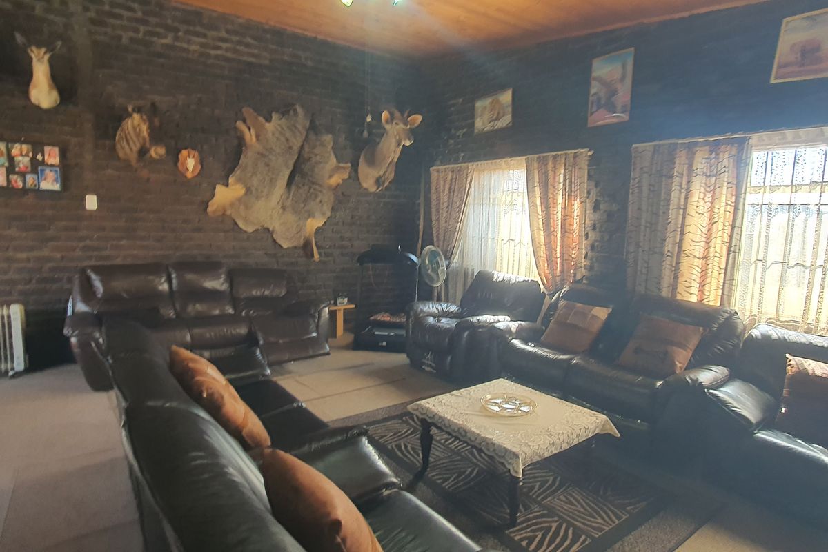 Spacious living room featuring exposed brick walls and a timber ceiling, offering a rustic aesthetic with large windows for natural light.