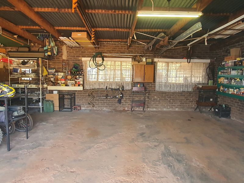 Spacious garage featuring exposed brick walls, corrugated metal roofing, and concrete flooring, providing ample storage and workspace potential.