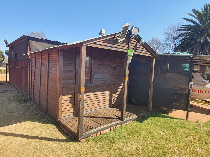 A timber-clad outbuilding featuring a small deck, corrugated roof, and integrated solar lighting, situated on a small holding property.