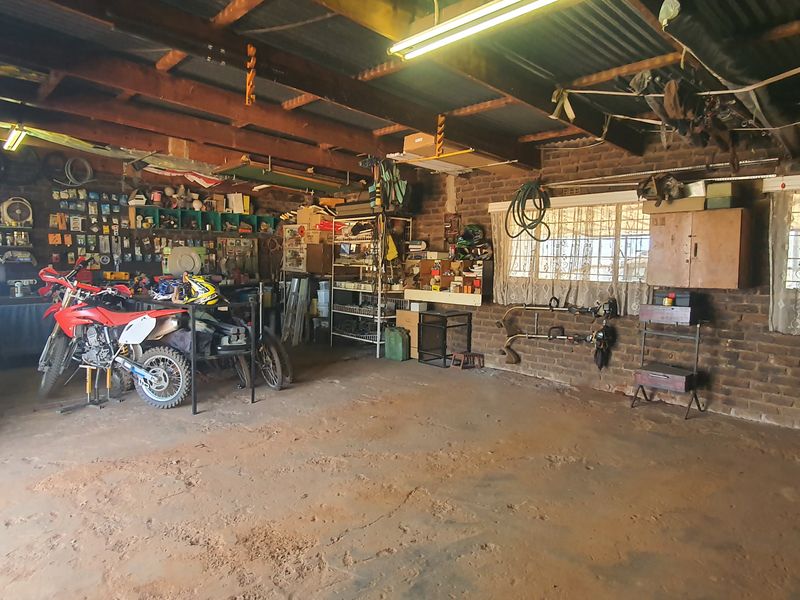 Spacious garage featuring exposed brick walls, timber roof trusses, and concrete flooring, offering ample storage or workshop potential.