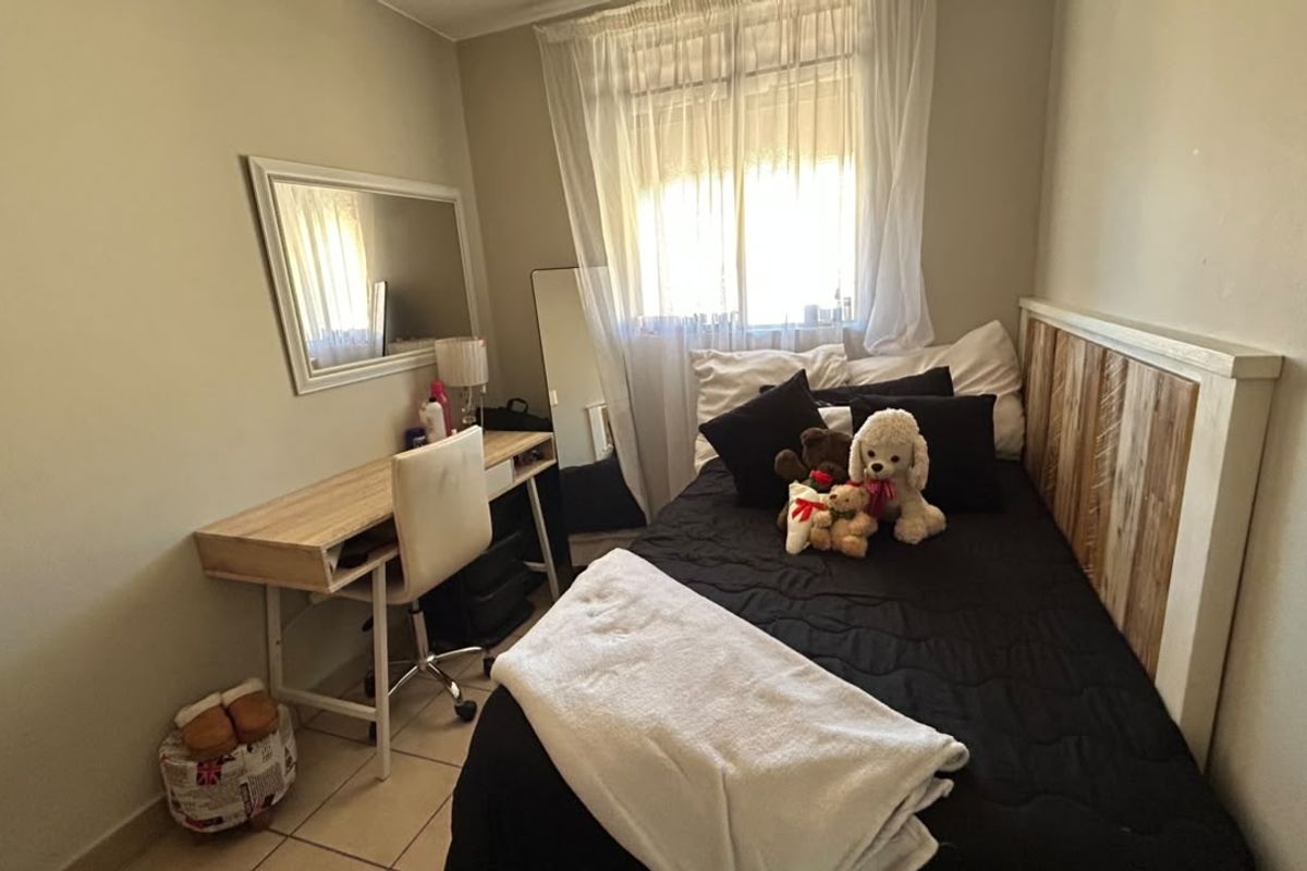 A compact bedroom featuring tiled flooring and a window with curtain rails, providing a functional space for rest.