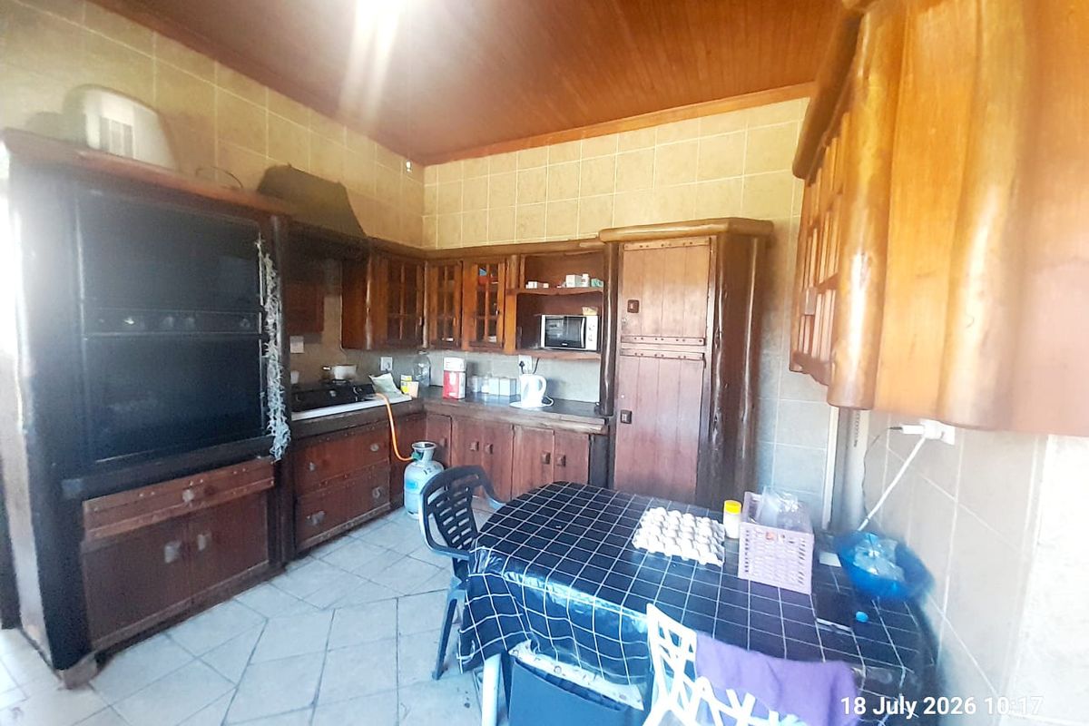 A rustic kitchen featuring extensive built-in wooden cabinetry, tiled backsplash, and a wooden ceiling, offering a traditional farm-style aesthetic in need of modernization.