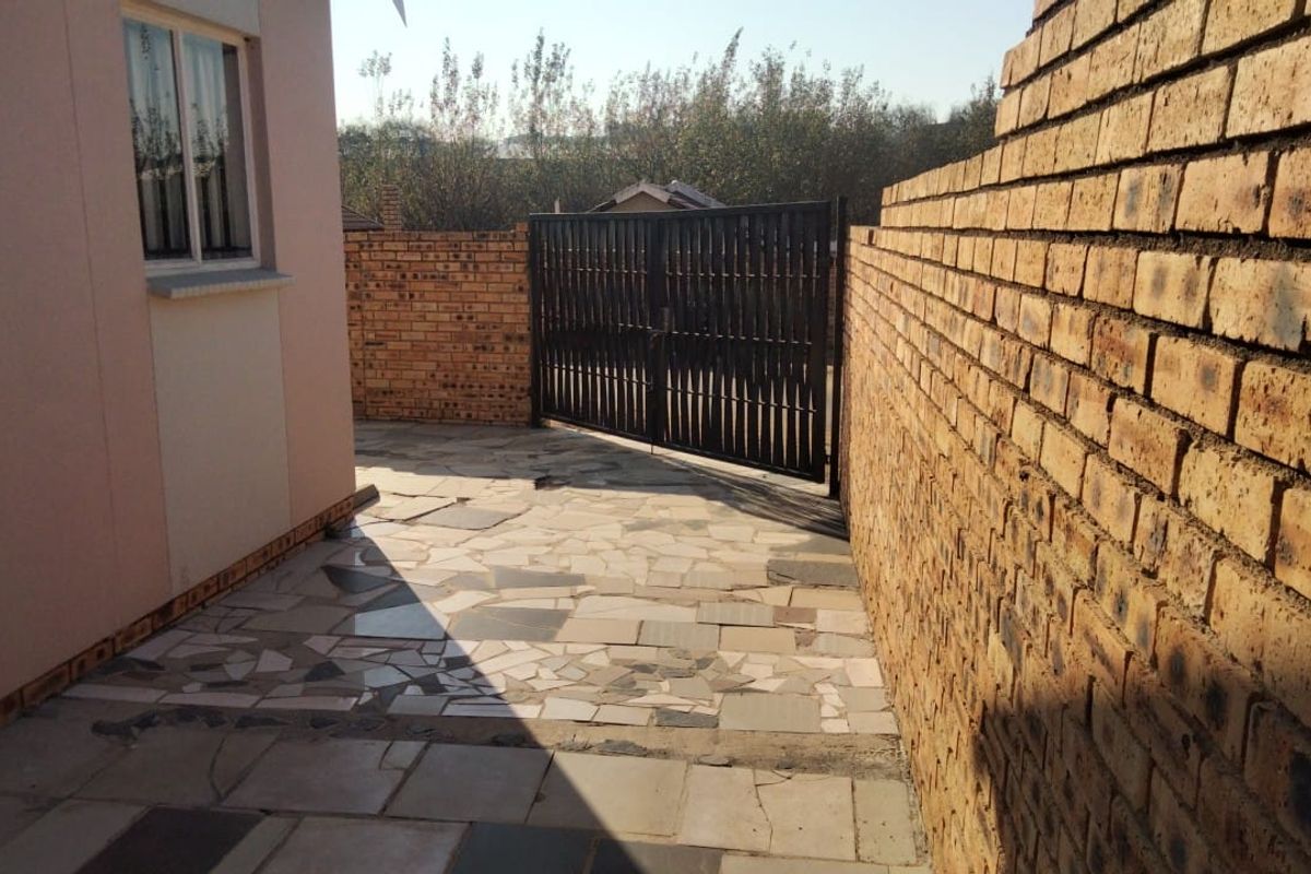 A private rear courtyard area featuring paved flooring, enclosed by facebrick boundary walls and secured with a metal gate.