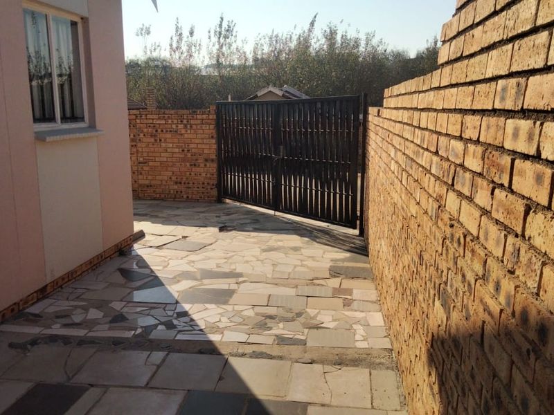 A private rear courtyard area featuring paved flooring, enclosed by facebrick boundary walls and secured with a metal gate.