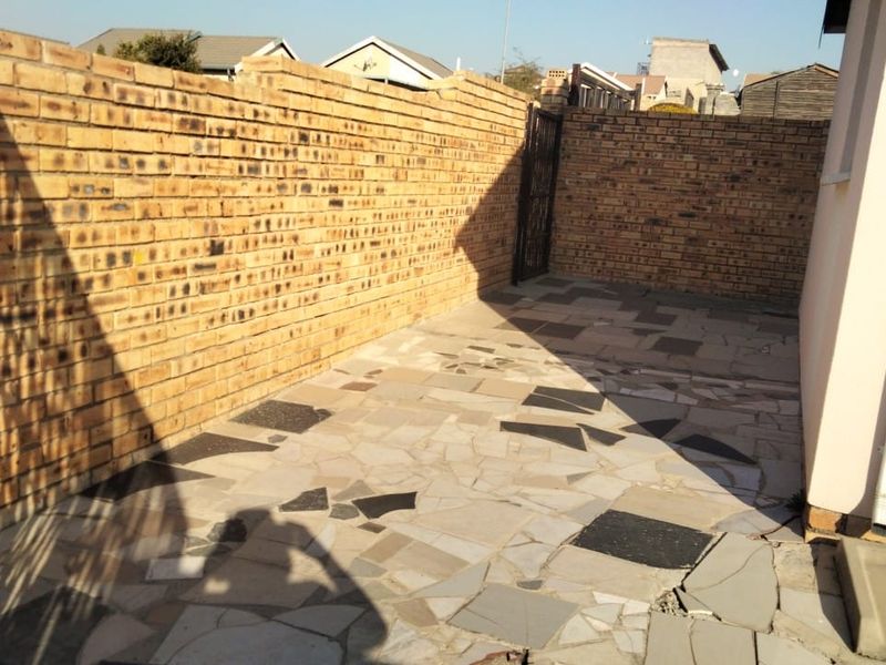 A private rear courtyard area featuring a face brick boundary wall and stone crazy paving, offering a secure outdoor space.