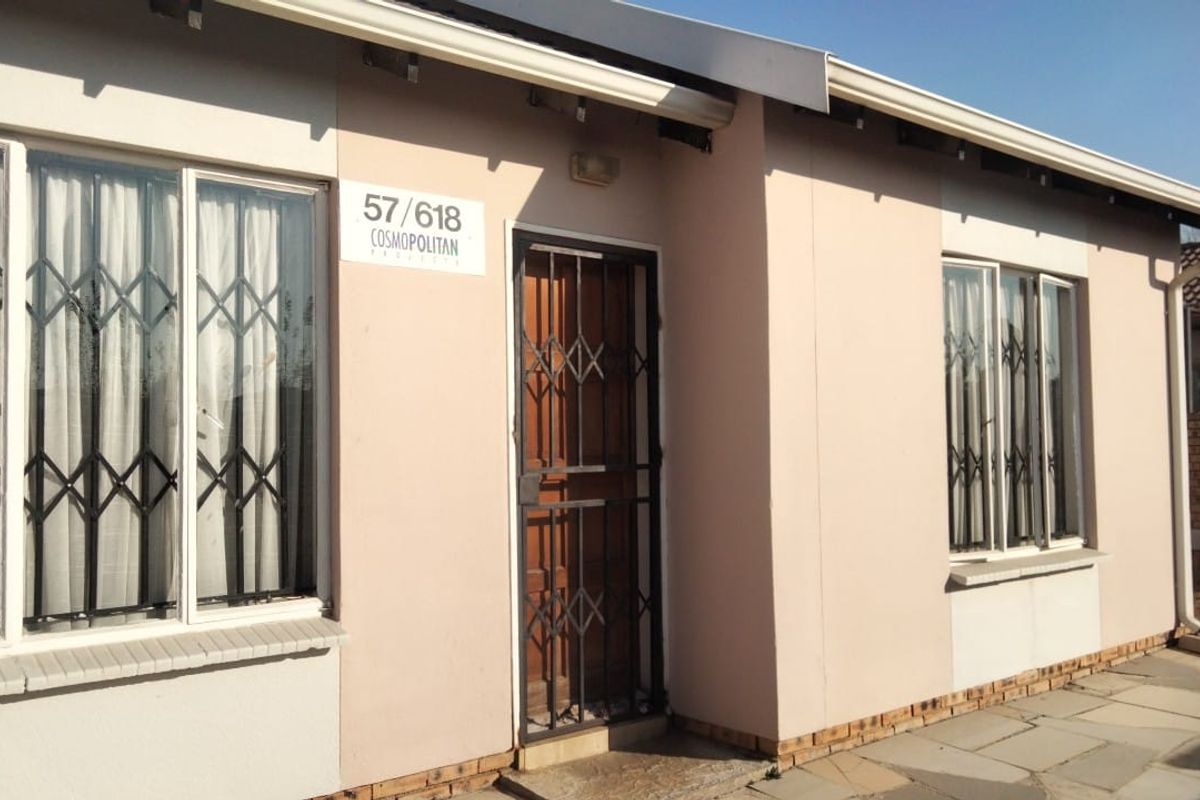 Front elevation of a cluster home featuring a security gate, aluminium window frames, and a paved walkway entrance.