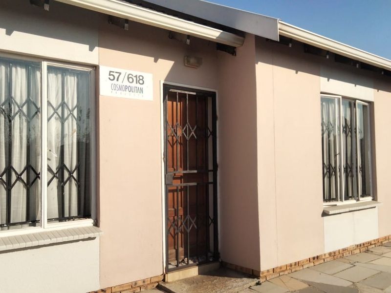 Front elevation of a cluster home featuring a security gate, aluminium window frames, and a paved walkway entrance.