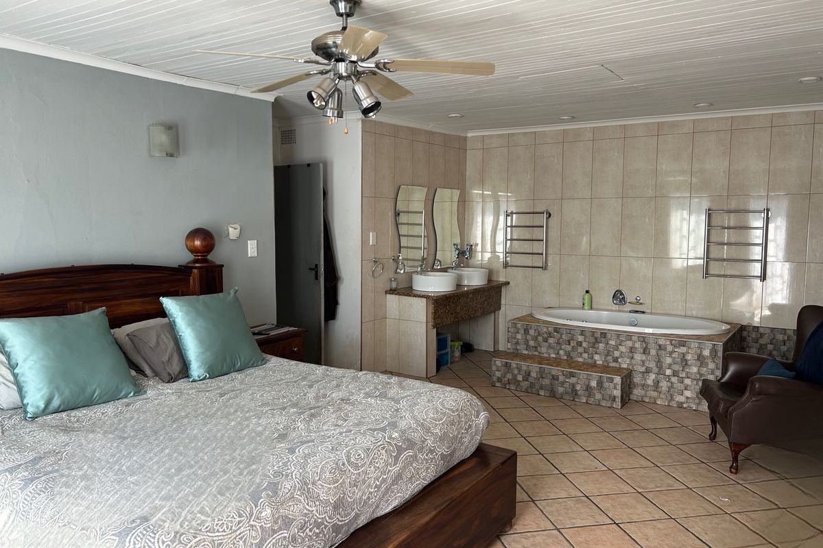 Spacious bedroom featuring an integrated en-suite bathroom with a built-in bathtub, dual vanity, and heated towel rails.