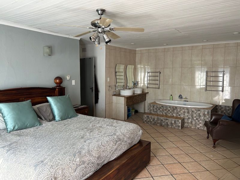 Spacious bedroom featuring an integrated en-suite bathroom with a built-in bathtub, dual vanity, and heated towel rails.