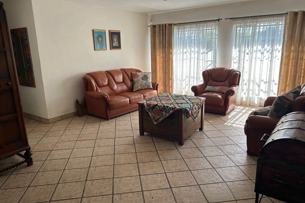 A spacious living room featuring neutral ceramic tile flooring and large windows with natural light, offering a comfortable and functional living space.