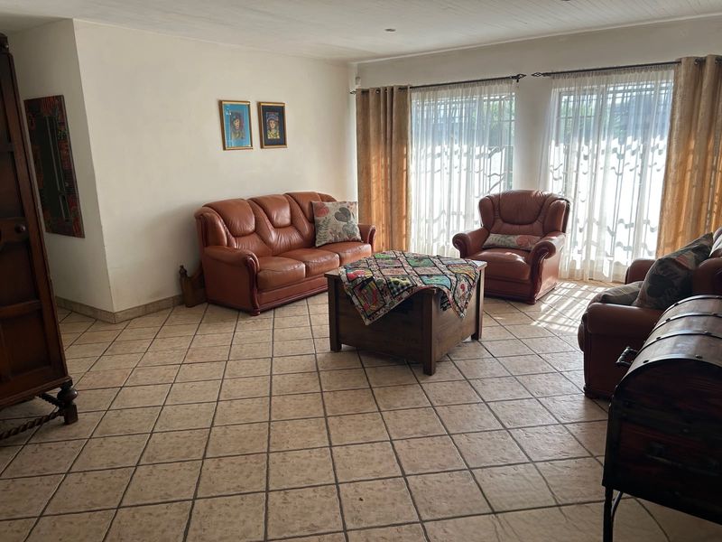 A spacious living room featuring neutral ceramic tile flooring and large windows with natural light, offering a comfortable and functional living space.