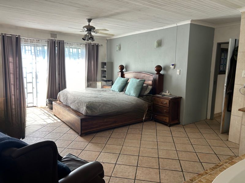 Spacious bedroom featuring tiled flooring, a ceiling fan, and large sliding glass doors that provide ample natural light.