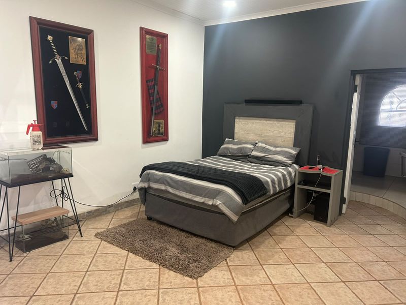 A bedroom featuring tiled flooring and a dark grey accent wall, providing a neutral base for potential interior design updates.