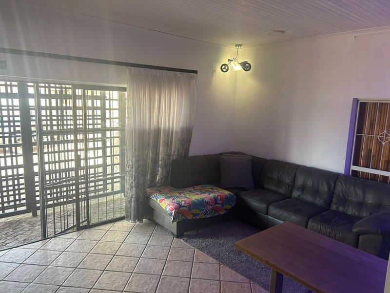 A living room featuring tiled flooring, a tongue and groove ceiling, and a sliding glass door with an integrated security gate.
