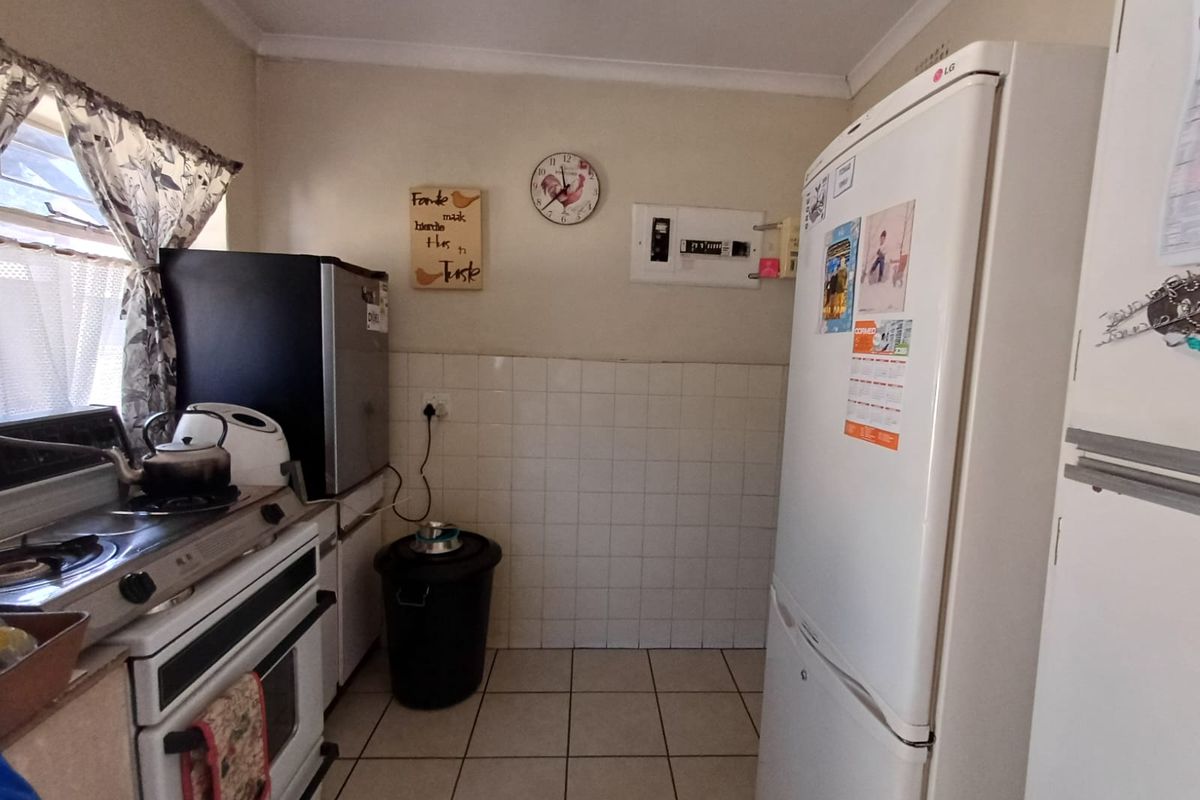 A functional kitchen area featuring tiled flooring, a tiled splashback, and a built-in electrical distribution board.