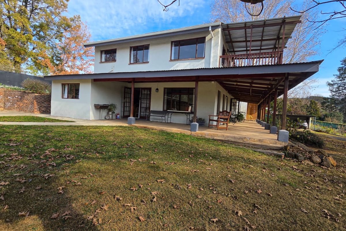 Rear view of a two-story dwelling featuring a spacious covered patio, an upper-level balcony, and a large garden area.