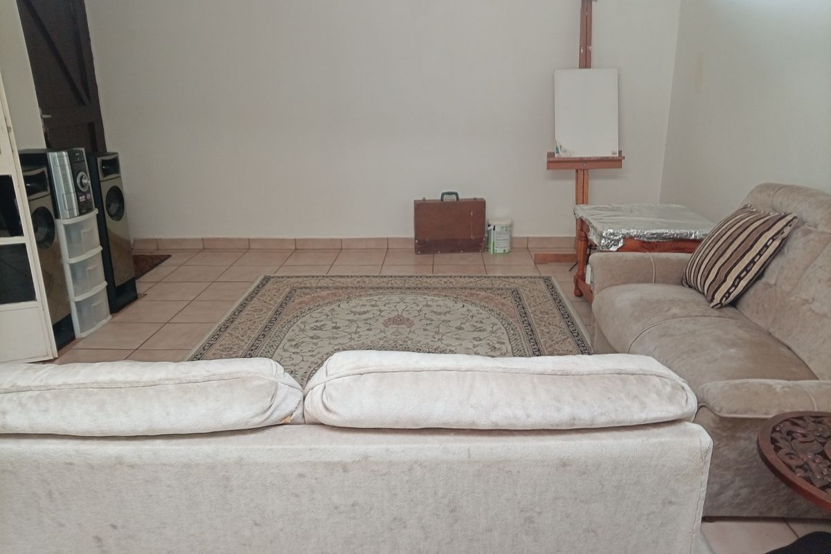 A living room area featuring neutral tiled flooring and a simple layout, offering a blank canvas for potential interior design updates.