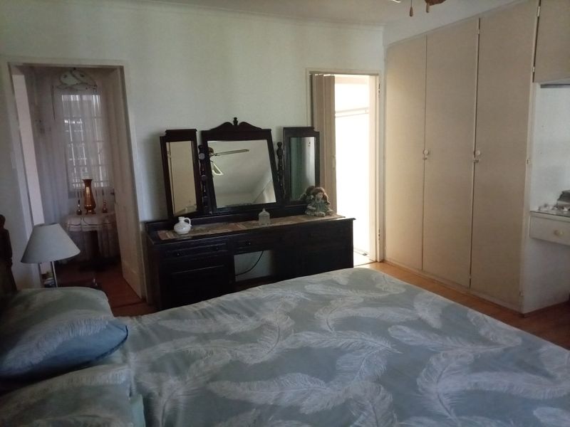 A bedroom featuring built-in cupboards and timber flooring, with direct access to an adjoining room.