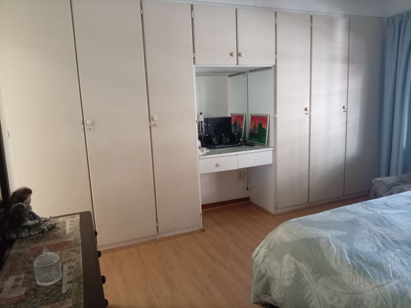 Bedroom featuring extensive built-in cupboards with an integrated vanity unit and light-toned laminate flooring.