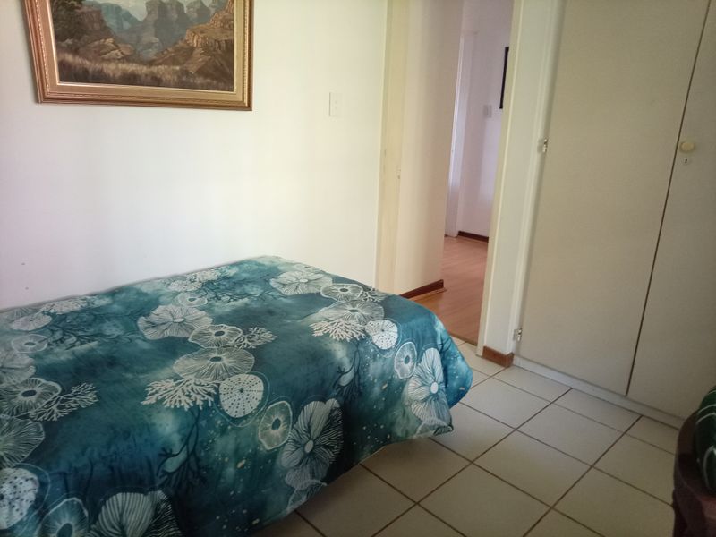 A bedroom featuring tiled flooring and a built-in wardrobe, providing functional storage space within the retirement village unit.