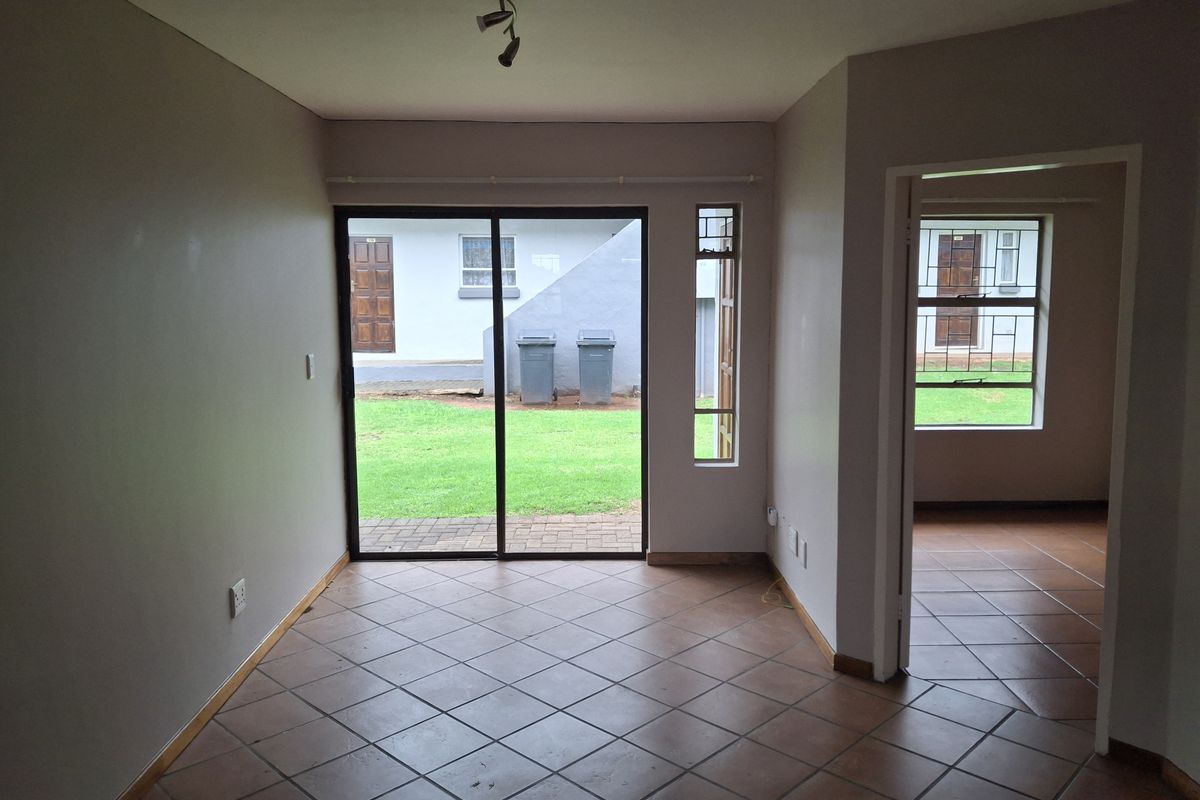 An empty living room featuring ceramic tile flooring, a sliding glass door leading to the exterior, and neutral wall finishes.
