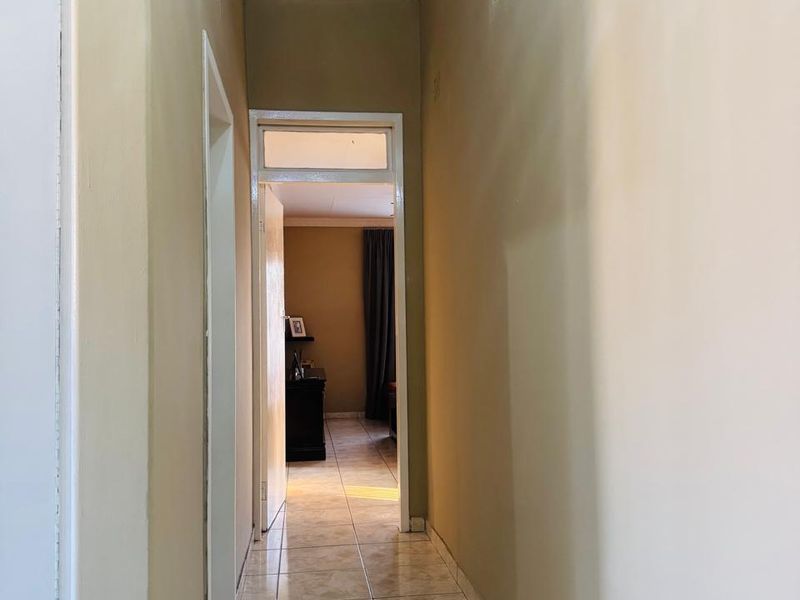 A functional hallway featuring neutral wall tones and tiled flooring, providing access to adjacent rooms within the home.