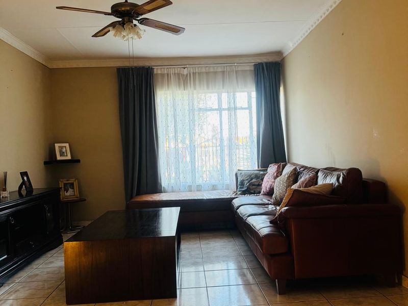 A living room featuring tiled flooring, a ceiling fan, and decorative cornice detailing, providing a functional and comfortable space.
