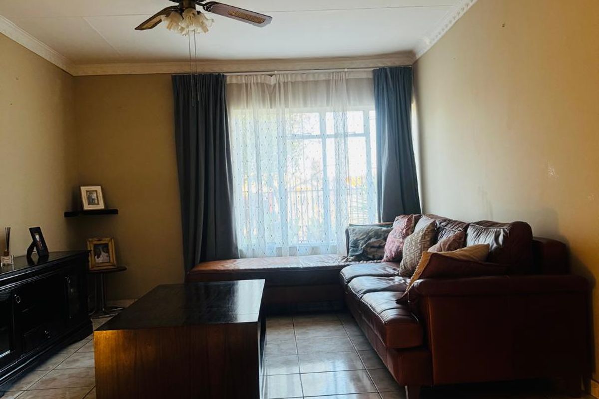A living room featuring tiled flooring, a ceiling fan, and decorative cornice detailing, providing a functional and comfortable space.