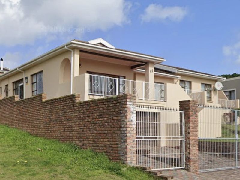 Front elevation of a residential house featuring a brick boundary wall, metal security gate, and a covered balcony area.