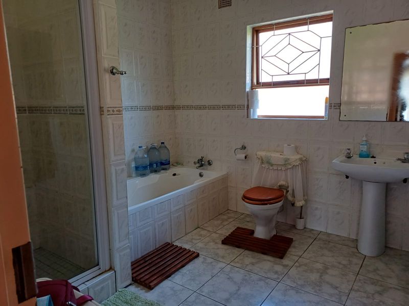 A functional bathroom featuring a shower enclosure, built-in bathtub, pedestal basin, and toilet with classic tiled finishes.