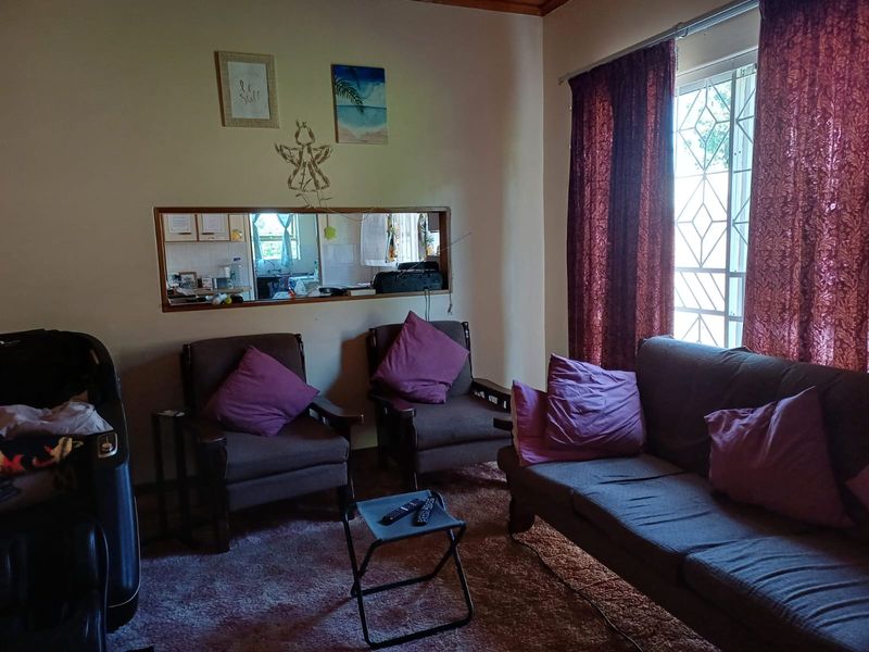 A living room featuring a serving hatch connecting to the kitchen area and a window with security gate.